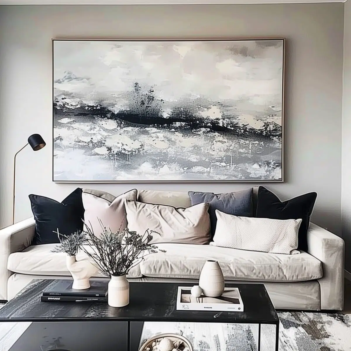 iphone_camera_large_blank_wall_ideas_living_rooms 12 An elegant lounge space, characterized by a large abstract black and white painting above a beige sofa, complemented by black and blue cushions.
