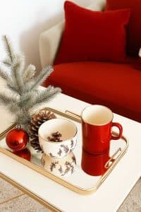 Get your festive on with a red mug, holiday bowl, and pine cone on a gold tray. Oh, and that tiny fake tree? Peak holiday vibes minus the pine needle mess. Add that red cushion’s snuggle factor and you've got yourself a cozy corner worthy of Instagram envy.