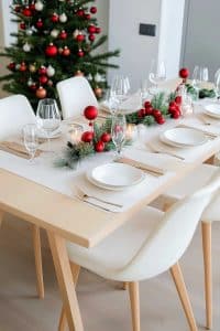 Alright, here's the deal: a sleek dining table decked out for Christmas, complete with pristine white dishes, glitzy glassware, festive candles and a glowing tree. Time to impress!