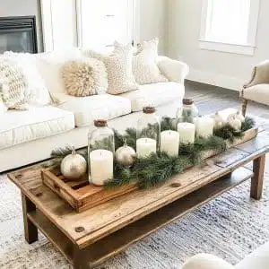 So here's a cozy living room where the wooden coffee table is trying its best to double as a festive forest. Think candles, pine branches, and ornaments giving it their all.