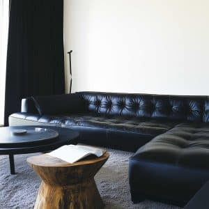 Modern living room alert: feast your eyes on this black leather sofa, paired with a round table and a wooden stump stool that shouts I camp, but make it fashion.