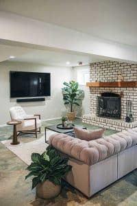 Imagine a living room where Netflix battles its toughest competitor: the white brick fireplace. With that sofa and armchair, you're snoozing in style, surrounded by potted plants doing their best to liven up your viewing experience.